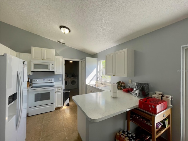 kitchen with kitchen peninsula, lofted ceiling, light tile flooring, white appliances, and independent washer and dryer