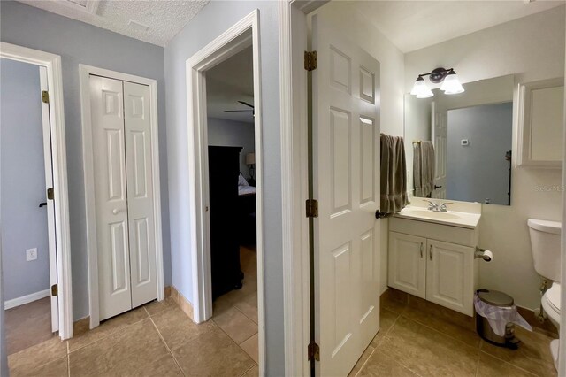 bathroom featuring vanity, tile flooring, ceiling fan, and toilet