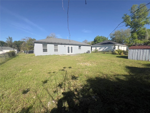 rear view of house with a lawn and a storage shed