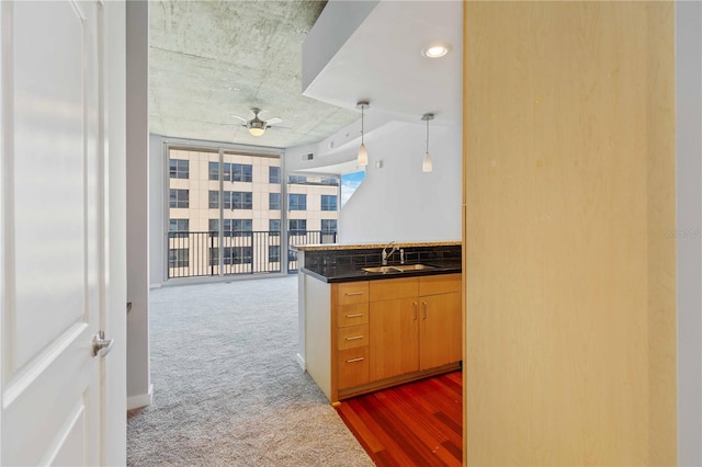 kitchen featuring backsplash, ceiling fan, a wall of windows, sink, and dark colored carpet