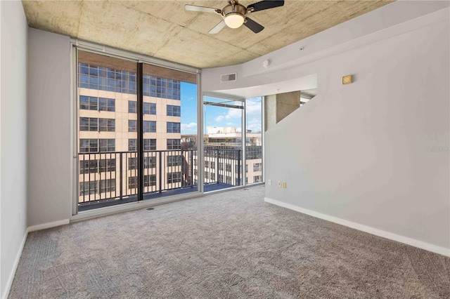 carpeted empty room with a wall of windows and ceiling fan