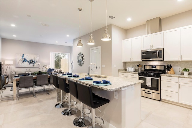 kitchen featuring pendant lighting, a kitchen bar, appliances with stainless steel finishes, white cabinets, and sink