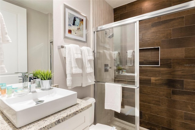 bathroom featuring toilet, an enclosed shower, and vanity