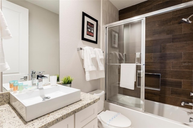 full bathroom with enclosed tub / shower combo, toilet, and vanity