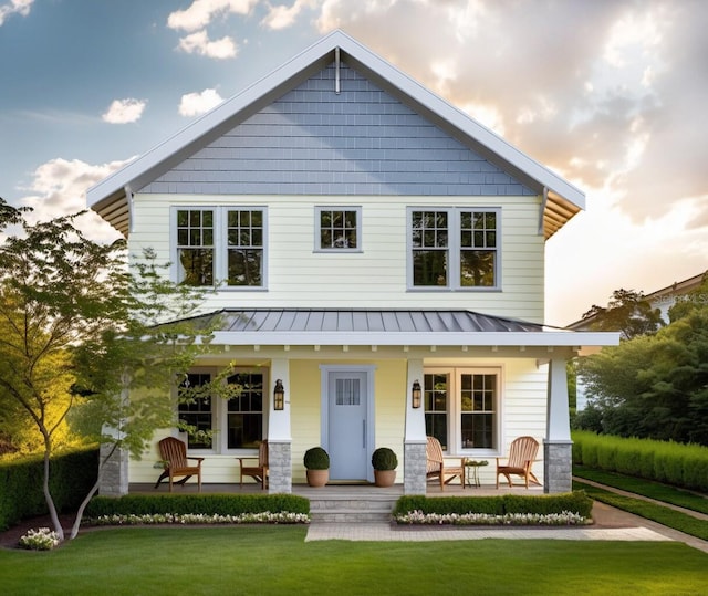 back house at dusk with a yard and covered porch