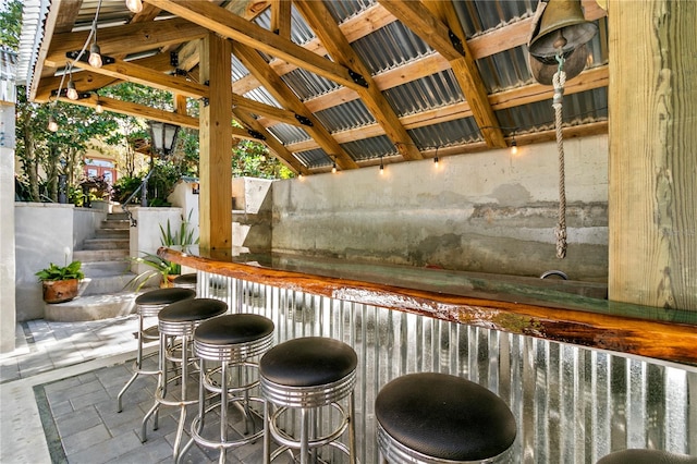 bar featuring lofted ceiling, stone tile floors, stairs, and a dry bar