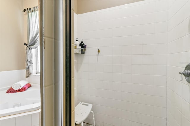 bathroom with a garden tub and a tile shower