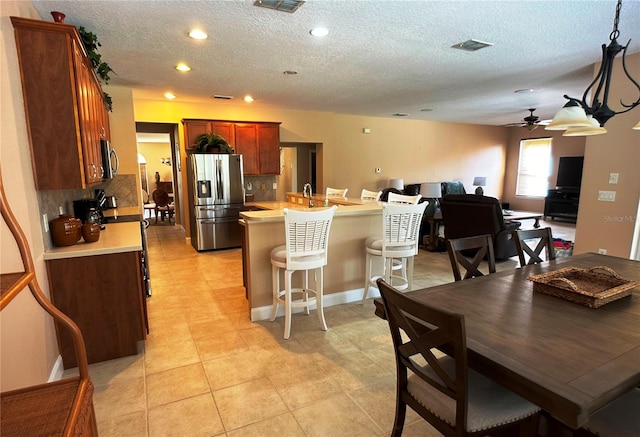 kitchen featuring kitchen peninsula, tasteful backsplash, a textured ceiling, stainless steel appliances, and ceiling fan