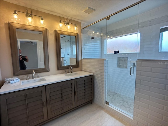 bathroom featuring vanity, a textured ceiling, an enclosed shower, and ceiling fan