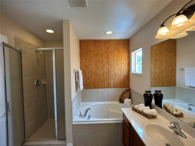 bathroom with vanity, a textured ceiling, and separate shower and tub