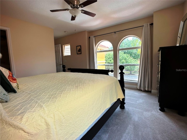 carpeted bedroom featuring ceiling fan and a textured ceiling