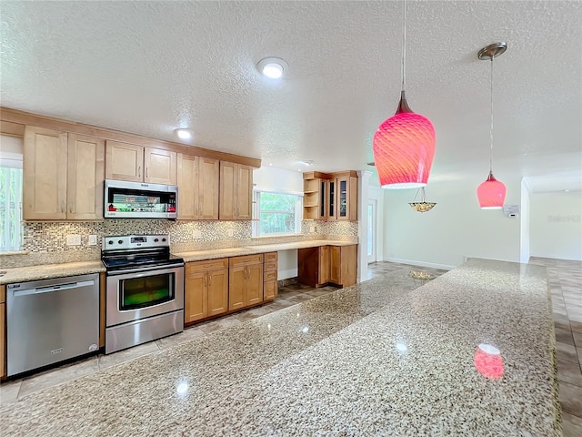 kitchen featuring light stone countertops, tasteful backsplash, a textured ceiling, stainless steel appliances, and hanging light fixtures