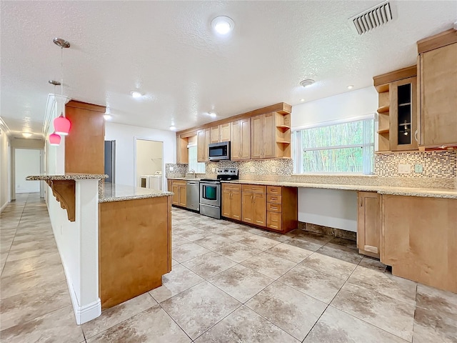 kitchen featuring light stone counters, kitchen peninsula, pendant lighting, a kitchen bar, and appliances with stainless steel finishes