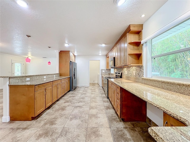 kitchen with kitchen peninsula, appliances with stainless steel finishes, backsplash, light stone counters, and hanging light fixtures