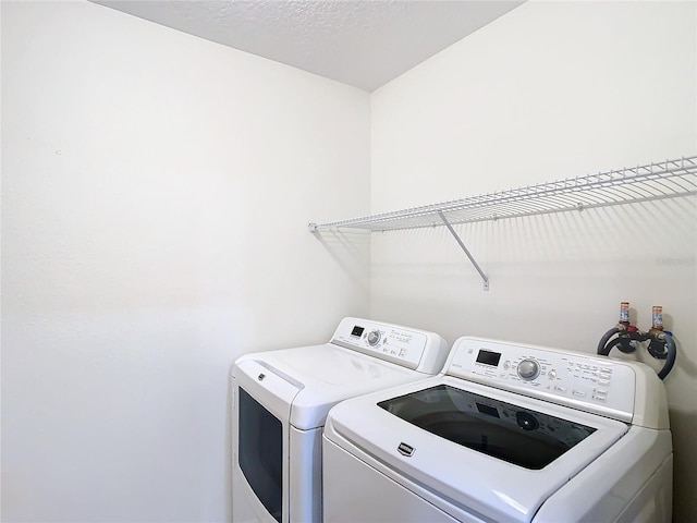 clothes washing area featuring a textured ceiling and washing machine and dryer