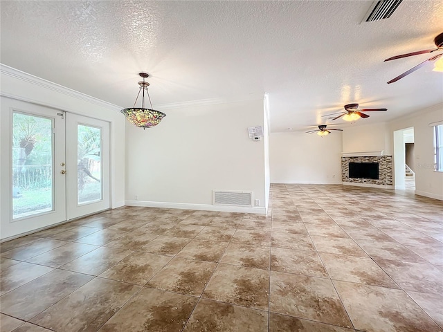 unfurnished living room with a fireplace, crown molding, french doors, and a textured ceiling