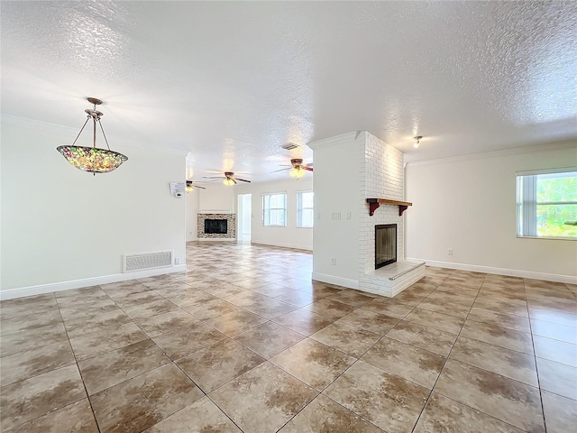 unfurnished living room featuring ceiling fan, a fireplace, a textured ceiling, and ornamental molding