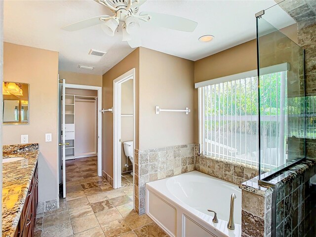 full bathroom with plus walk in shower, vanity, toilet, and ceiling fan