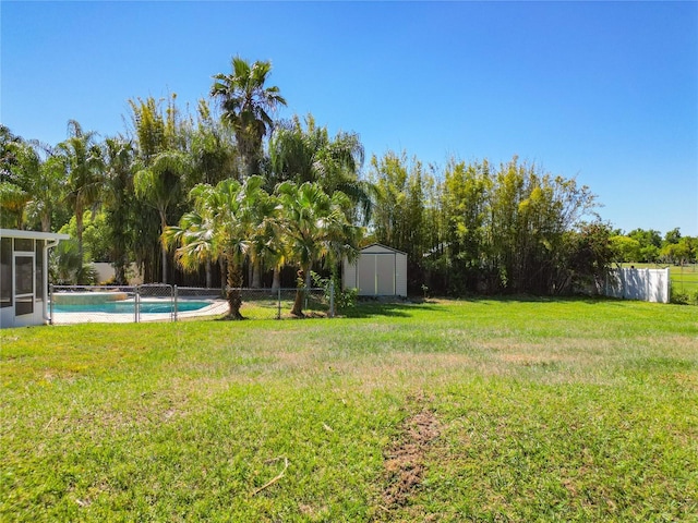 view of yard featuring a fenced in pool and a storage shed