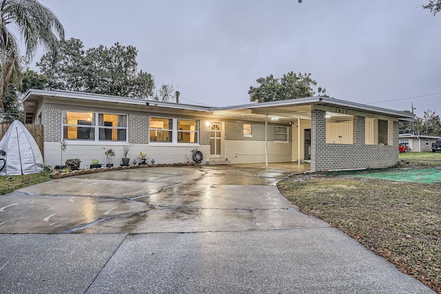 view of front of property featuring brick siding, concrete driveway, and a carport