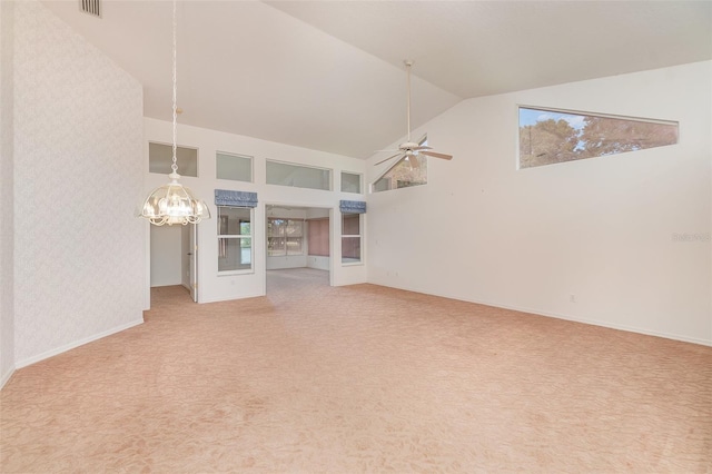 carpeted empty room featuring high vaulted ceiling and ceiling fan with notable chandelier