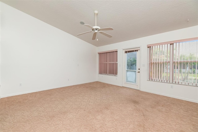 empty room featuring a textured ceiling, light colored carpet, ceiling fan, and lofted ceiling