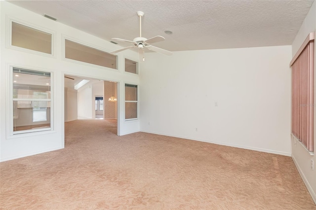 spare room with a textured ceiling, light colored carpet, and ceiling fan