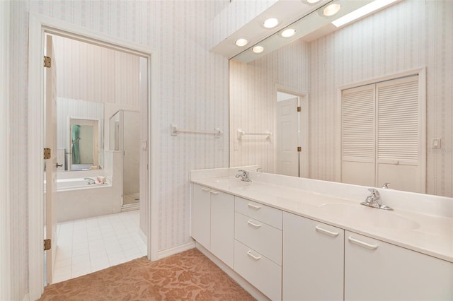 bathroom featuring a bath to relax in, oversized vanity, tile floors, and dual sinks