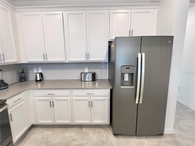 kitchen featuring white cabinets, light countertops, backsplash, range, and stainless steel fridge