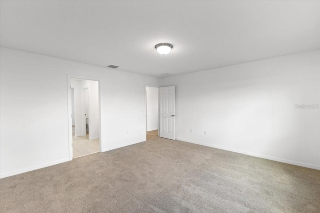 empty room with light carpet and a textured ceiling