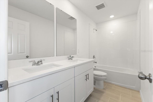 full bathroom with tiled shower / bath, vanity, and toilet