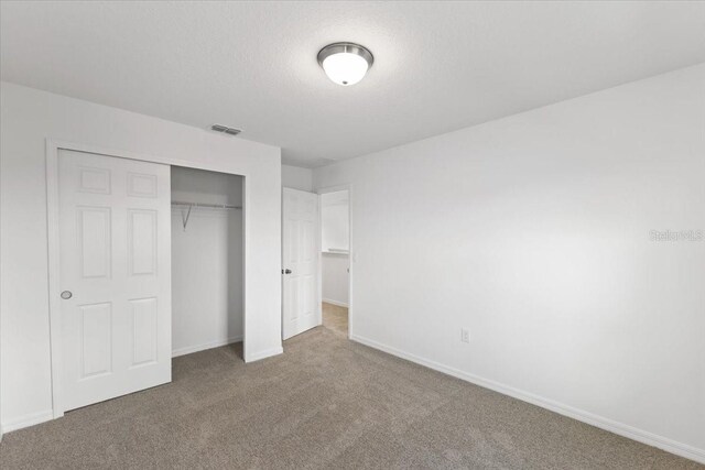 unfurnished bedroom with carpet flooring, a closet, and a textured ceiling