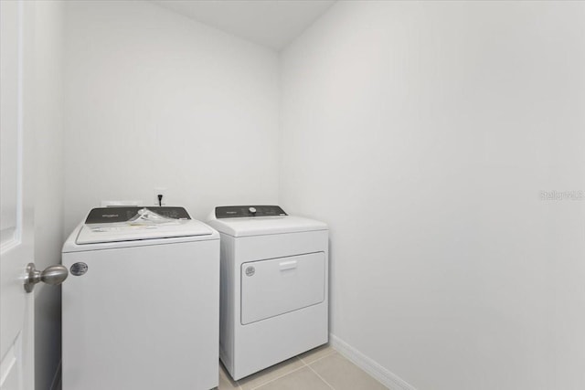 clothes washing area featuring light tile patterned flooring and separate washer and dryer