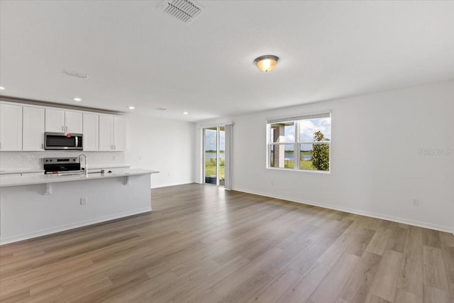 kitchen with white cabinetry, a breakfast bar area, stainless steel appliances, and light wood-type flooring