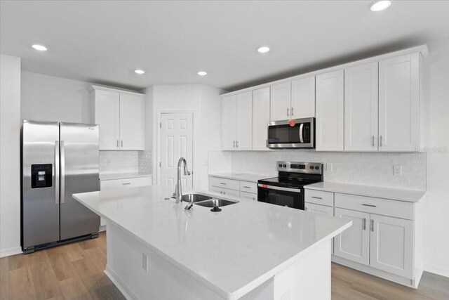 kitchen featuring a kitchen island with sink, sink, white cabinetry, and appliances with stainless steel finishes