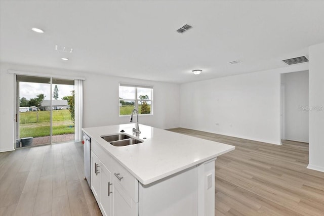 kitchen with sink, dishwasher, an island with sink, light hardwood / wood-style floors, and white cabinets