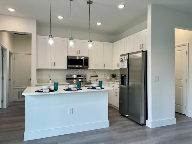 kitchen with decorative light fixtures, an island with sink, white cabinets, and appliances with stainless steel finishes