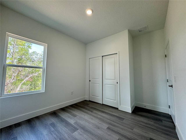 unfurnished bedroom featuring hardwood / wood-style floors, a closet, and a textured ceiling