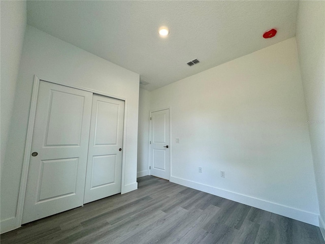 unfurnished bedroom featuring a closet, hardwood / wood-style floors, and a textured ceiling