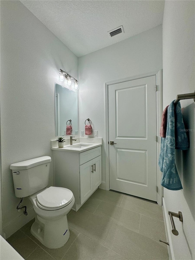 bathroom with a textured ceiling, toilet, and vanity