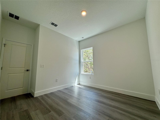 empty room with dark wood-type flooring and a textured ceiling