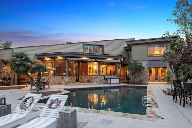 pool at dusk with a patio area