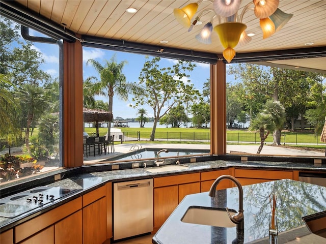 interior space with black electric stovetop, dishwasher, dark stone countertops, and sink