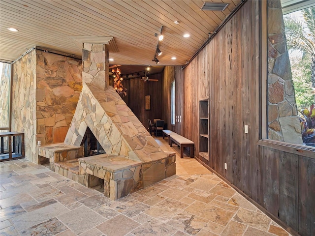 interior space featuring wood ceiling, wooden walls, and an outdoor stone fireplace