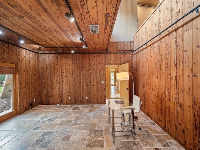 unfurnished room with wood ceiling, track lighting, and wood walls