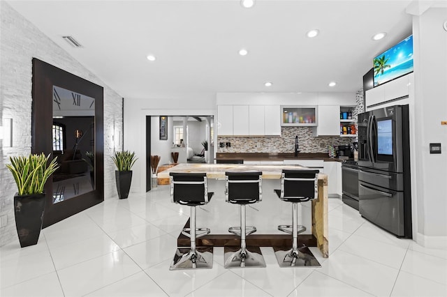 kitchen with a breakfast bar area, white cabinets, backsplash, a center island, and stainless steel appliances