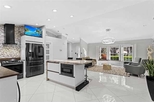 kitchen featuring decorative light fixtures, vaulted ceiling, light tile patterned floors, stainless steel appliances, and wall chimney range hood