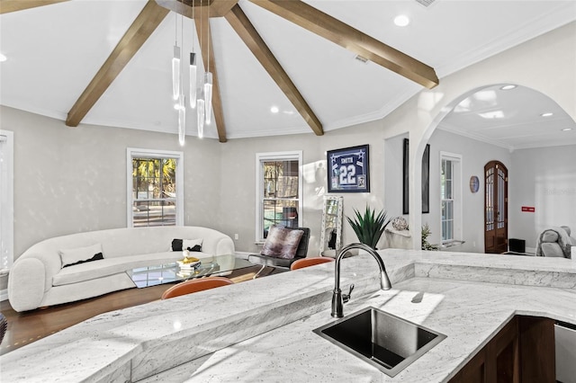 kitchen featuring lofted ceiling with beams, light stone countertops, and sink