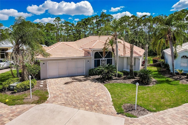 mediterranean / spanish-style home with a garage and a front lawn