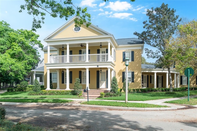 neoclassical / greek revival house featuring a balcony, a porch, and a front lawn